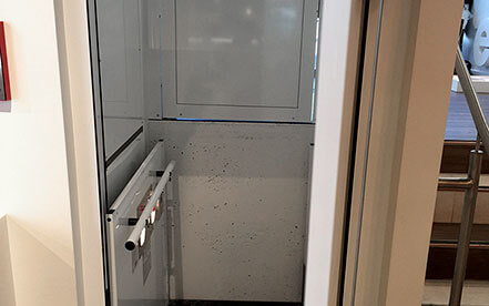 Genesis shaftway model vertical platform lift for wheelchairs with open swinging hall door