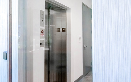 Elvoron LULA elevator application thumbnail showing lift with glass doors and natural light in corridor setting – Garaventa Lift