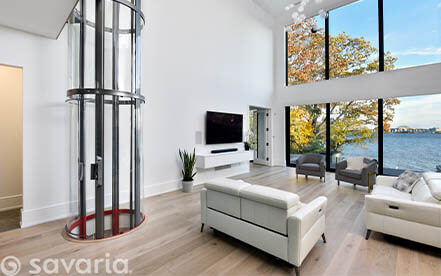 Glass home elevator in a contemporary waterfront living room with large windows