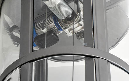 Close-up view of residential glass elevator mechanical components through transparent cab.