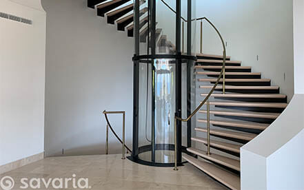 Glass residential elevator in a bright open-concept home interior