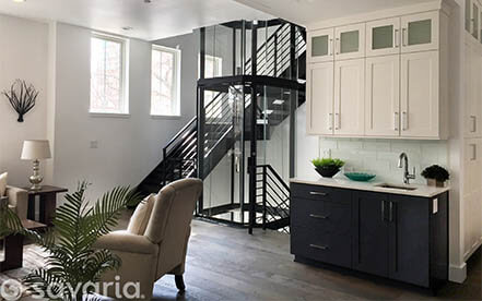 Glass residential elevator installed in a modern waterfront living room
